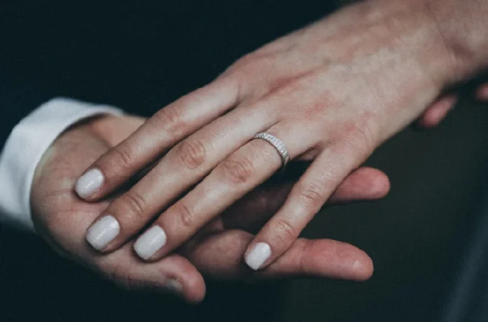 Elegant diamond engagement ring on woman's hand with neutral manicure