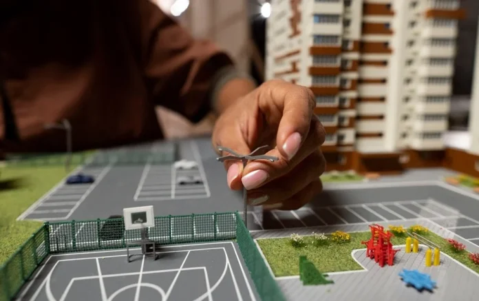 Off-Plan Real Estate Investments in 2025 – Model Planning & Development A person placing a miniature streetlight on a real estate model, showcasing off-plan property investment opportunities in 2025.