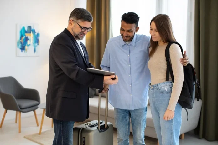 A couple with luggage talking to a travel agent while planning their trip, highlighting the importance of the best travel insurance.