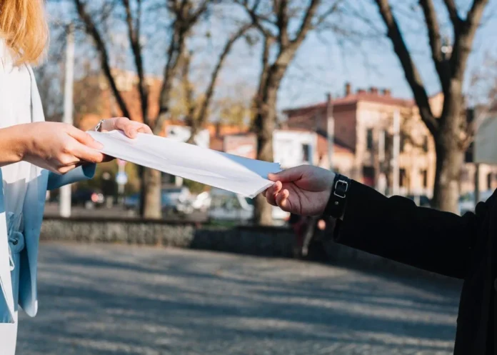 A person handing over a legal document outdoors, symbolizing the European Arrest Warrant process in cross-border justice.