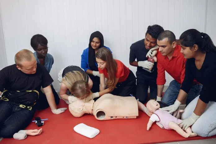 A diverse group of employees participating in a first aid training session, practicing CPR on a mannequin to improve workplace safety.