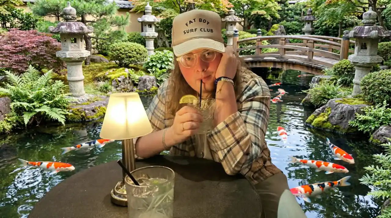 Landon Bridges sitting at a table in a Japanese-style garden with koi fish, enjoying a casual outdoor moment.