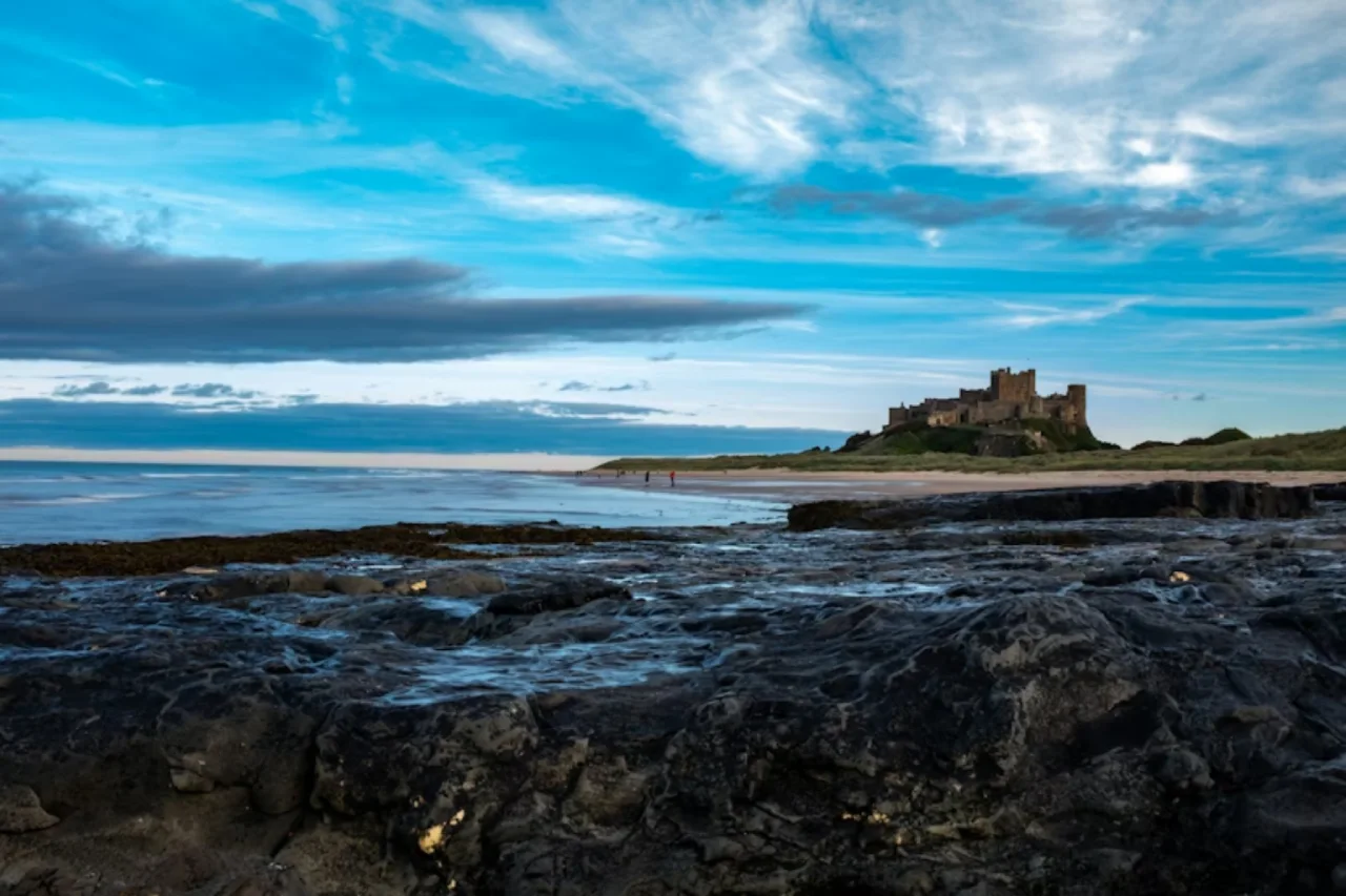 a castle sitting on top of a rocky beach next to the ocean