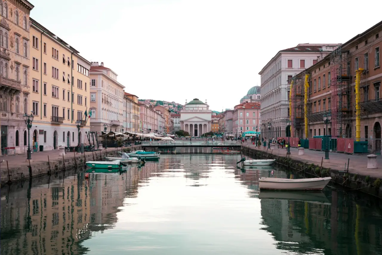 Trieste Grand Canal Italy ke saath pastel buildings aur boats ka evening view